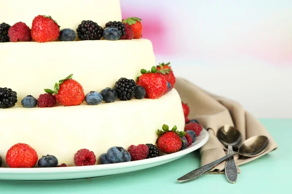 Beautiful wedding cake with berries on wooden table, on light background — Stock Photo, Image