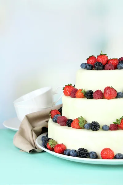 Beautiful wedding cake with berries on wooden table, on light background — Stock Photo, Image