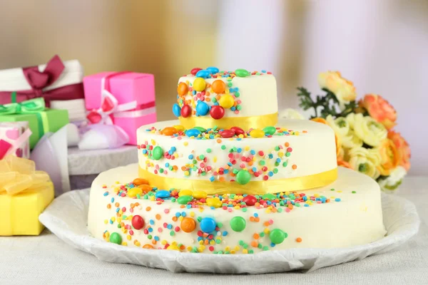 Bolo de aniversário saboroso bonito e presentes no fundo de cor — Fotografia de Stock