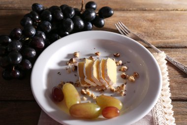 lezzetli üzüm ve ahşap masa üzerinde plaka üzerinde peynir