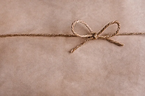 Paper texture with rope bow, close-up — Stock Photo, Image