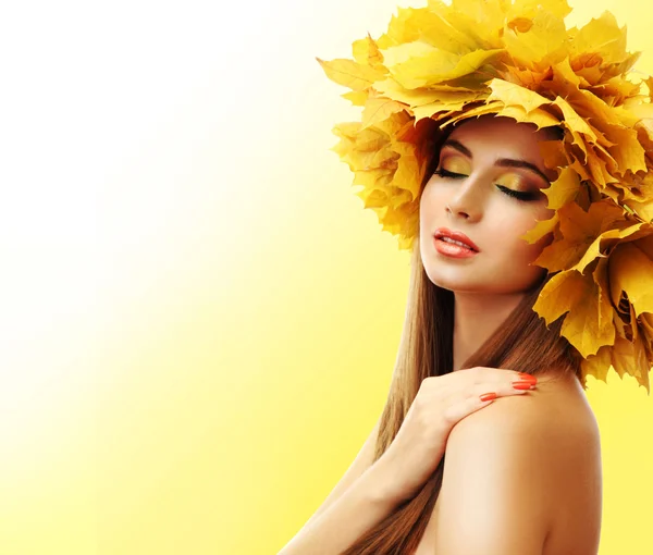 Beautiful young woman with yellow autumn wreath on yellow background — Stock Photo, Image