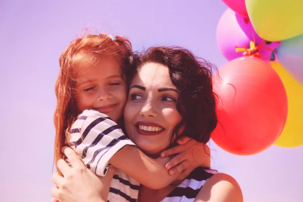 Mãe feliz e filha com balões — Fotografia de Stock