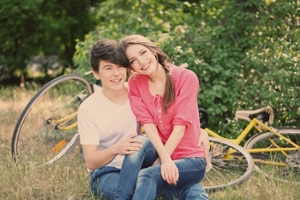Jovem casal sentado no parque com bicicletas — Fotografia de Stock
