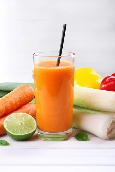 Glas färsk morotsjuice och grönsaker på träbord — Stockfoto