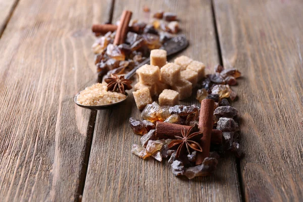 Bruna sockerbitar, reed och kristall socker, kryddor på trä bakgrund — Stockfoto