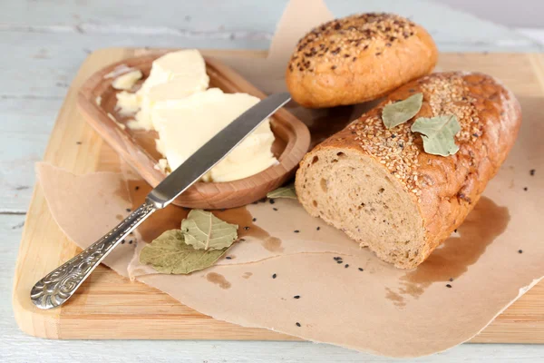 Pane al forno e burro fresco, sul tagliere, su fondo di legno — Foto Stock