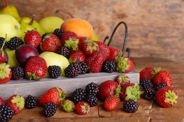 Rijp fruit en bessen op lade houten achtergrond — Stockfoto