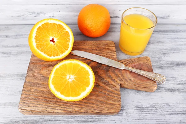 Glass of juice with fresh orange on grey wooden table — Stock Photo, Image