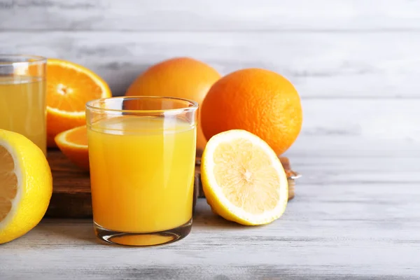 Glas juice med färsk frukt på grå träbord — Stockfoto