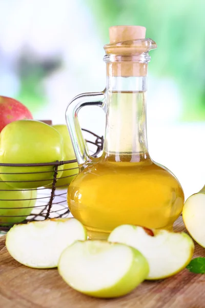 Cuka sari apel dalam botol kaca dan apel matang segar, di atas meja kayu, di latar belakang alam — Stok Foto