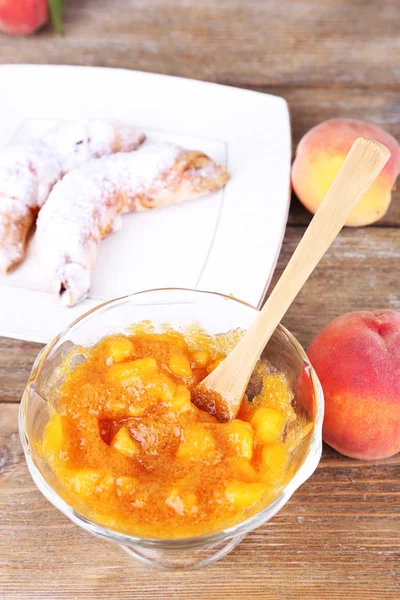 Tasty peach jam with fresh peaches and croissants on wooden table — Stock Photo, Image