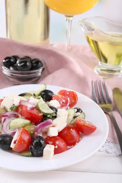 Salată grecească servită în farfurie cu pahar de vin pe șervețel pe masă de lemn pe fundal natural — Fotografie, imagine de stoc