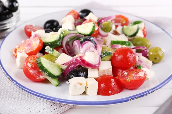 Salada grega servida em prato sobre guardanapo em fundo de madeira — Fotografia de Stock
