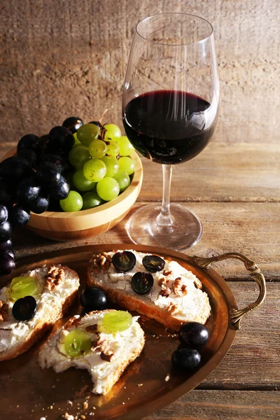 Bella natura morta con vino, formaggio e uva matura su sfondo di legno — Foto Stock