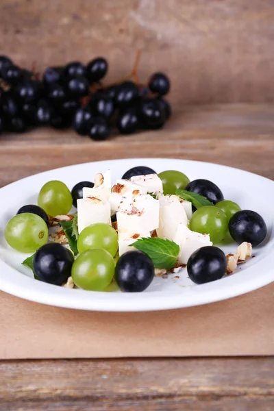 Tasty salad with grape and cheese on wooden table — Stock Photo, Image