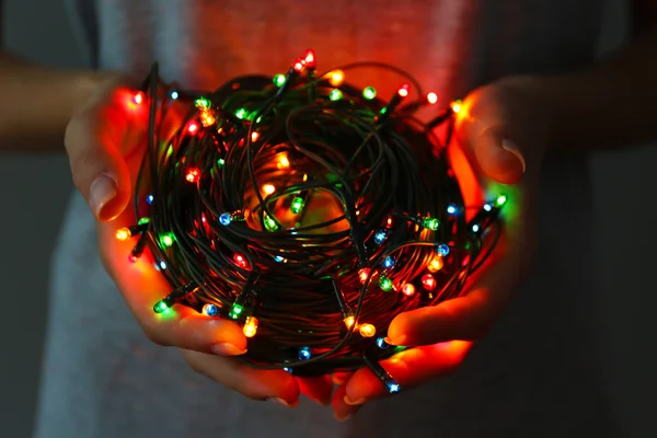 Vrouw bedrijf veelkleurige garland op donkere achtergrond — Stockfoto