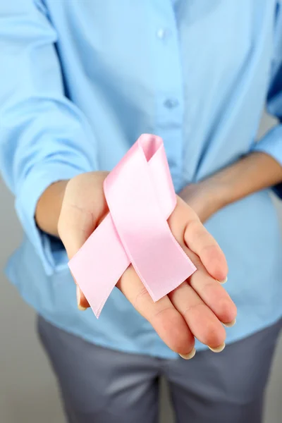 Mulher segurando fita rosa no fundo claro — Fotografia de Stock