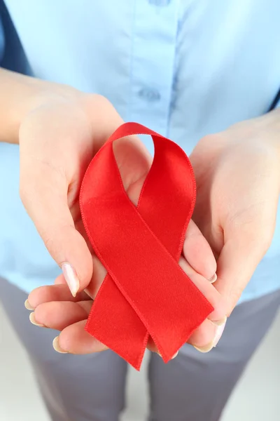Woman holding red ribbon on light background — Stock Photo, Image