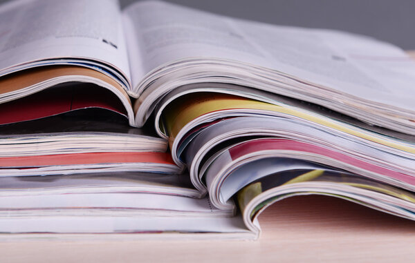 Журналы на деревянном столе на сером фоне

