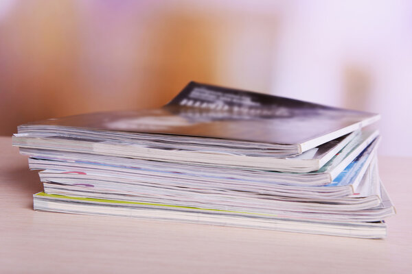 Журналы на деревянном столе на ярком фоне
