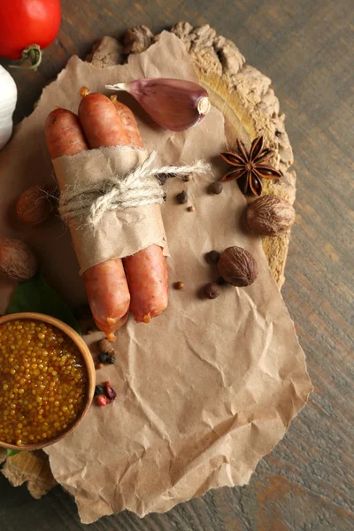 Composizione di salsicce sottili, senape in ciotola e spezie su fondo di legno — Foto Stock