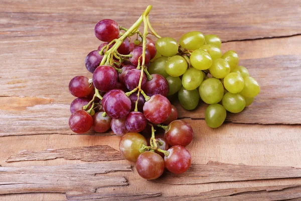 Bunches of different kinds of grapes on wooden background — Stock Photo, Image