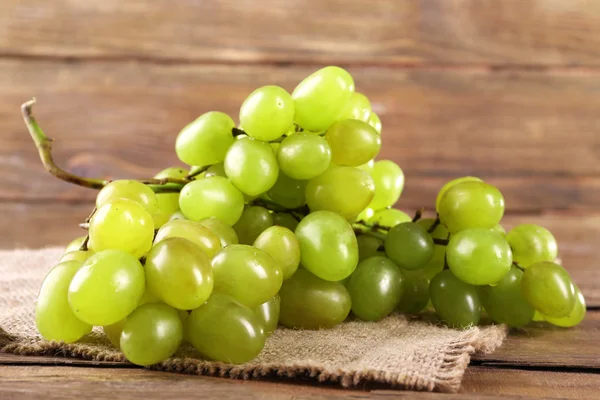 Bunch of ripe grape on napkin on wooden table on wooden wall background — Stock Photo, Image