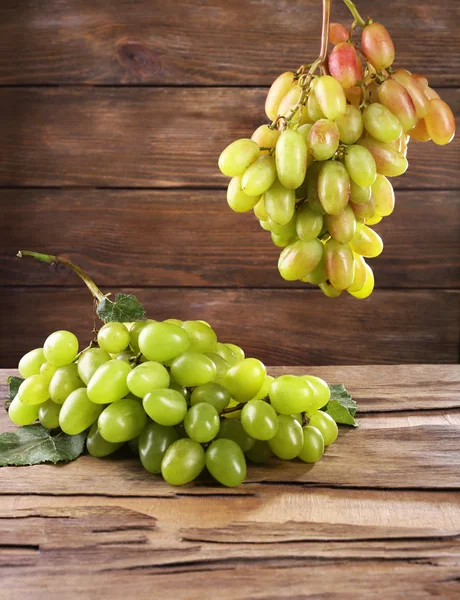 Des grappes de raisins mûrs sur table en bois sur fond de mur en bois — Photo