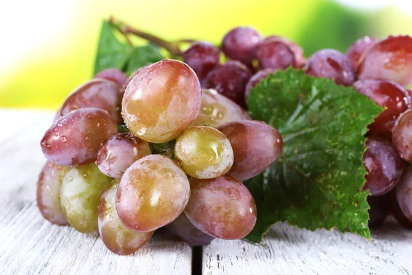 Bunch of ripe grape on wooden table on natural background — Stock Photo, Image