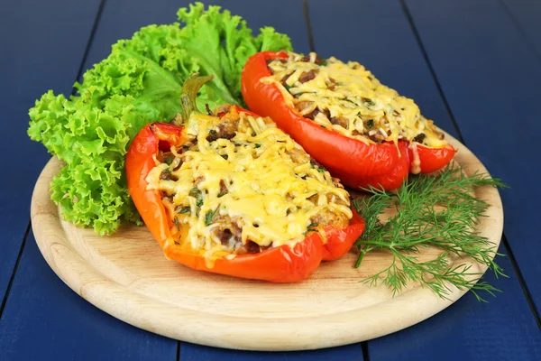 Stuffed red peppers with greens on wooden stand on table close up — Stock Photo, Image