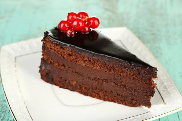 Torta al cioccolato con bacche fresche sul piatto, su sfondo di legno a colori — Foto Stock