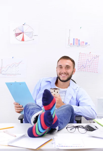 Businessman holding legs on desk