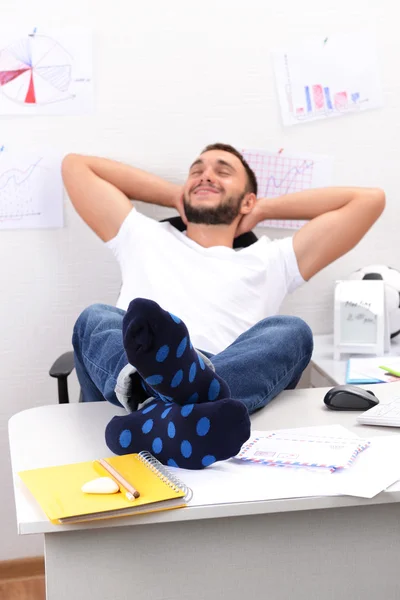 Businessman holding legs on desk — Stock Photo, Image