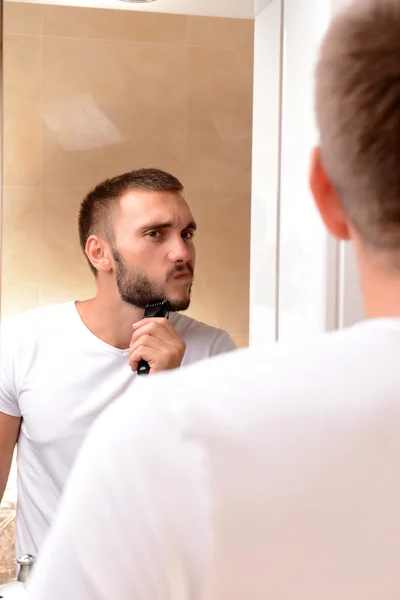 Jovem barbear sua barba no banheiro — Fotografia de Stock