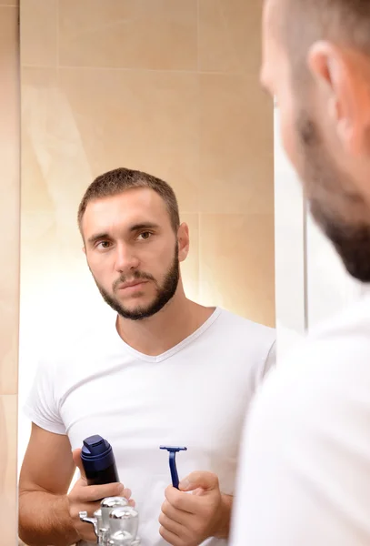 Fiatal férfi borotválja a szakállát a fürdőszobában — Stock Fotó