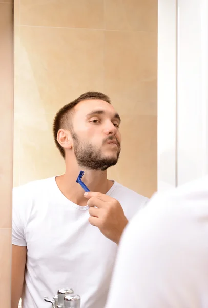 Ο νεαρός ξυρίζει τα γένια του στο μπάνιο. — Φωτογραφία Αρχείου