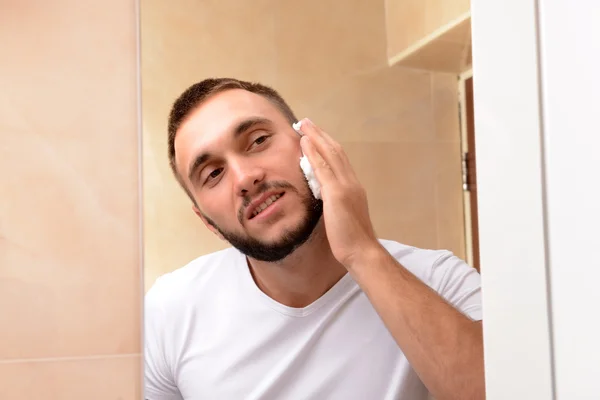 Jovem barbear sua barba no banheiro — Fotografia de Stock