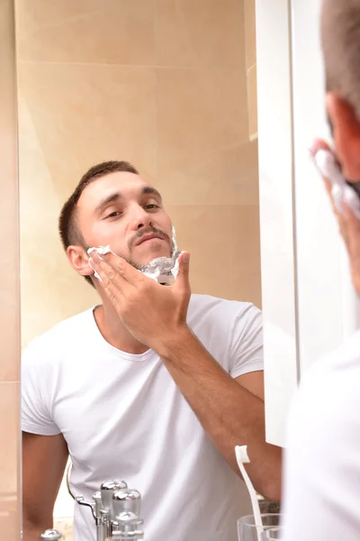 Jovem barbear sua barba no banheiro — Fotografia de Stock