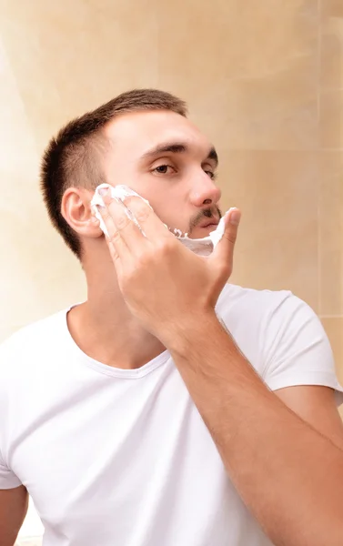 Jeune homme rasant sa barbe dans la salle de bain — Photo