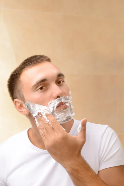 Jeune homme rasant sa barbe dans la salle de bain — Photo