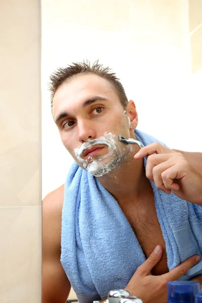 Junger Mann rasiert sich im Badezimmer den Bart — Stockfoto
