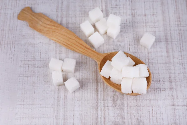 Sucre raffiné blanc dans une cuillère en bois sur fond bois — Photo