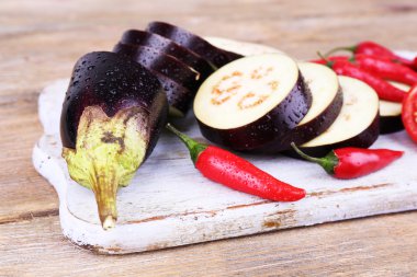 Doğranmış patlıcan ve ahşap arka plan üzerinde kesme tahtası üzerinde serin biber