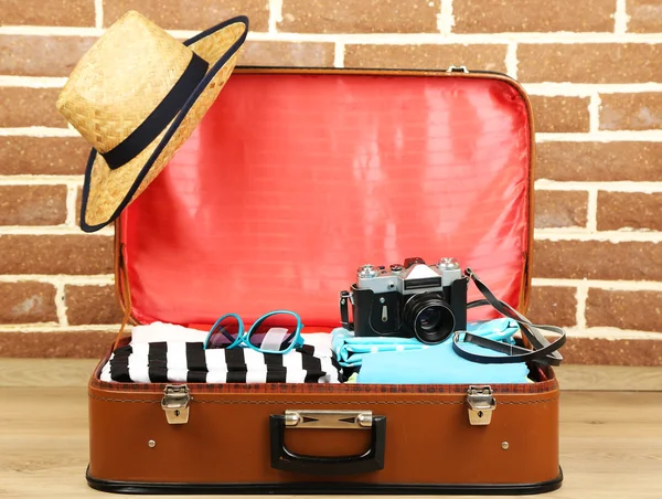 Female clothes in old suitcase on brick wall background