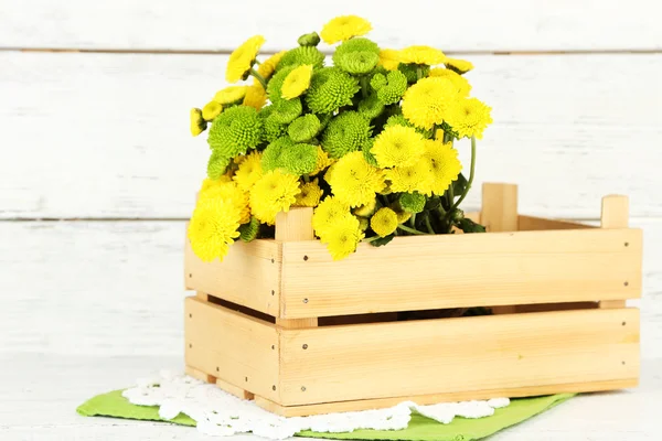 Желтые и зеленые цветы в деревянной коробке, на деревянном фоне — стоковое фото