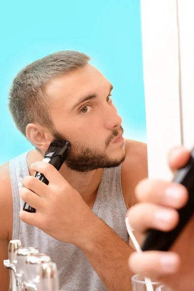 Young man shaving his beard in bathroom — Stock Photo, Image