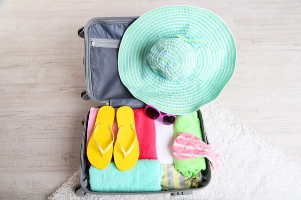 Bőrönd, fehér szőnyeg a padlón, utazás valahol közel a víz, a kiadások nyaralás a dolgokat — Stock Fotó