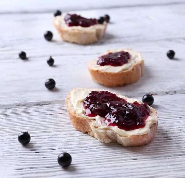 Fresh bread with homemade butter and blackcurrant jam on wooden background — Stock Photo, Image