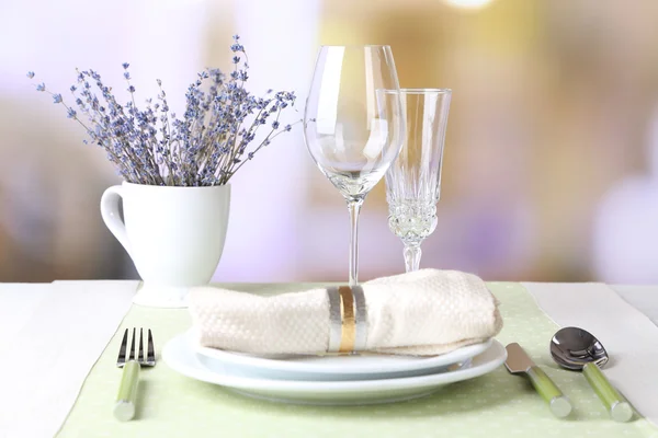 Apparecchiatura tavolo da pranzo con fiori di lavanda sul tavolo, su sfondo luminoso — Foto Stock